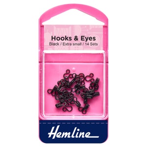 May include: A pack of 14 sets of black extra small hooks and eyes. The hooks and eyes are in a clear plastic container with a pink background. The pack is labelled "Hooks & Eyes" and "Black / Extra small / 14 Sets". The brand name "Hemline" is printed on the bottom of the pack.
