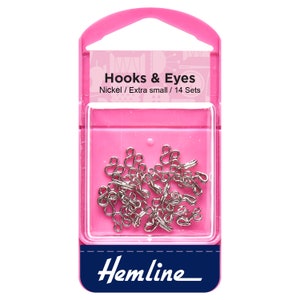 May include: A pink plastic pack with a clear window showing silver hooks and eyes. The pack says "Hooks & Eyes" and "Nickel / Extra small / 14 Sets". The bottom of the pack says "Hemline".