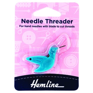 May include: A turquoise blue plastic needle threader shaped like a bird with a blade to cut threads. The packaging is pink with the text "Needle Threader" and "For hand needles with blade to cut threads". The brand name "Hemline" is printed in black at the bottom.