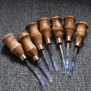 May include: A set of seven hand tools with contoured wooden handles featuring varied brown wood grain patterns. Each tool has a metal ferrule, a straight metal shaft, and a clear plastic protective tip covering the end of the metal blade.