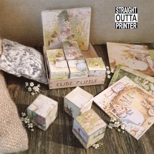 May include: A cube puzzle with illustrations of cats and rabbits, with the text "CUBE PUZZLE" on the box. The image also includes other illustrated cards and the text "STRAIGHT OUTTA PRINTER".