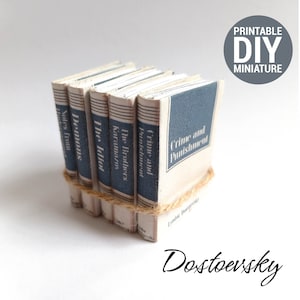 May include: A stack of miniature books with blue and white covers. The titles include "Crime and Punishment", "The Brothers Karamazov", "The Idiot", "Demons", and "Notes from Underground". The books are bound with twine and labeled "Dostoevsky".
