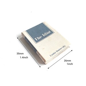 May include: A miniature book titled "The Idiot" by Fyodor Dostoevsky. The book is 1.4 inches tall and 1 inch wide.
