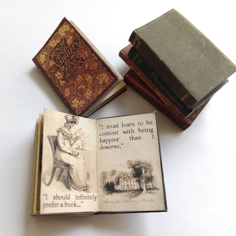 Op de afbeelding: Een verzameling miniatuurboeken, waaronder "Sense and Sensibility" van Jane Austen, "Northanger Abbey" en "Persuasion". De boeken zijn open op pagina's met citaten uit de romans.