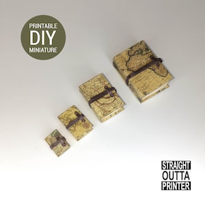 May include: Four miniature books with a vintage map design, secured with brown leather straps and clasps. The image includes the text "PRINTABLE DIY MINIATURE" and "STRAIGHT OUTTA PRINTER". The books are in varying sizes.