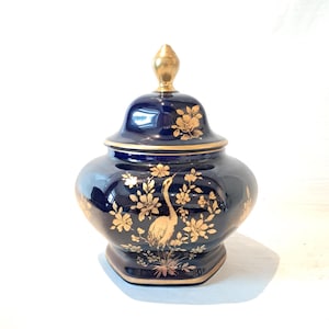 Op de afbeelding: Een kobaltblauwe keramische pot met een gouden deksel en een gouden bloemen- en vogelontwerp.