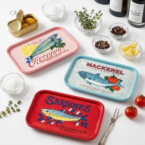 May include: Three rectangular ceramic serving trays featuring colorful illustrations of fish. One pink tray labeled Anchovies, one light blue tray labeled Mackerel, and one red tray labeled Sardines, each with detailed text and fish graphics.
