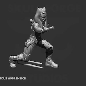 Op de afbeelding: Een grijs 3D-geprint miniatuur van een vrouwelijke figuur in een outfit met capuchon, die een wapen vasthoudt en in een vechtpose staat. De figuur is geposeerd met één been naar voren en het andere been gebogen bij de knie. De figuur draagt een outfit met capuchon met een lange, vloeiende cape. De figuur houdt een wapen vast in haar rechterhand. De figuur staat op een grijze basis.