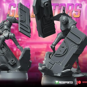May include: Two gray robot figures with shields, posed as if in combat. The figures are on a base with the word "Gladiators" in the background. The War Bear Studios logo is in the lower left corner. The figures are pre-supported.