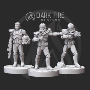 May include: Three gray plastic action figures of Star Wars clone troopers. The figures are posed in different stances, with one holding a blaster rifle, one holding a blaster pistol, and one holding a helmet. The figures are standing on circular bases.