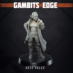 以下が含まれることがあります： 「Gambits Edge」の女性キャラクターの灰色のフィギュア。尖った耳があり、長いコート、ボディアーマー、ブーツなど、未来的な衣装を着ています。「GAMBITS EDGE」と「HESS VALEX」の文字が見えます。