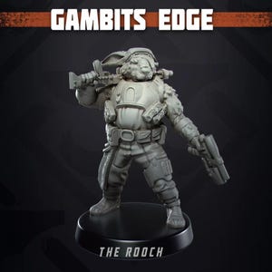 May include: A gray figurine of a rabbit-like character in military gear, holding a rifle and a pistol. The figurine is on a black base with the text "THE ROOCH". The text "GAMBITS EDGE" is at the top.