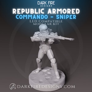 May include: A grey plastic miniature figure of a Republic Commando soldier holding a rifle. The figure is standing on a round base with a textured surface. The text "REPUBLIC ARMORED COMMANDO - SNIPER" is above the figure. The text "LED COMPATIBLE MODULAR KIT" is below the figure.