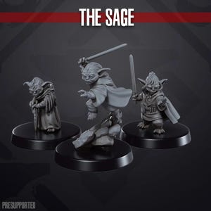 Könnte beinhalten: Drei graue Plastikfiguren von Yoda aus Star Wars. Die Figuren stehen auf schwarzen runden Sockeln. Der Text "THE SAGE" befindet sich oben im Bild.