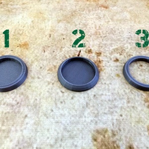 May include: Three different sized, round, grey plastic bases, labelled 1, 2, and 3. The bases are designed for use with miniature figures.