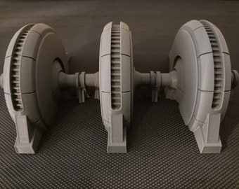 May include: Three gray, 3D printed, round, gear-like objects connected by a central shaft. Each object has a series of raised, rectangular panels around the circumference.