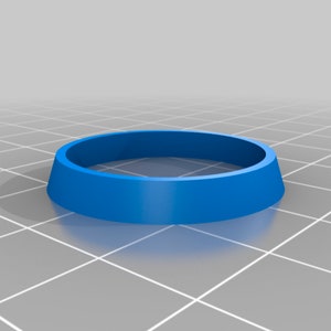 Puede incluir: Un anillo de plástico azul con una parte superior plana y un borde ligeramente elevado. El anillo tiene un diámetro de aproximadamente 5 cm.
