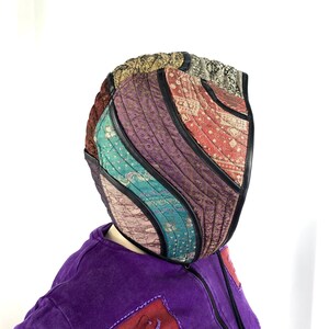 May include: A purple hoodie with a colourful patchwork hood. The hood is made of different fabrics and has a quilted design.