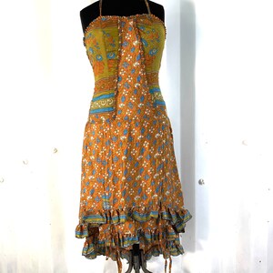 May include: A sleeveless, orange and green floral print dress with a blue and green trim. The dress has a fitted bodice and a flowing skirt with multiple layers of ruffles.