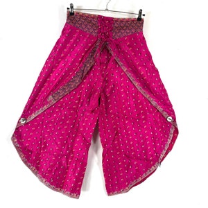 May include: Hot pink palazzo pants with a wrap-style design. The pants feature a delicate floral pattern and decorative trim along the edges. They are hanging on a black hanger against a white background.