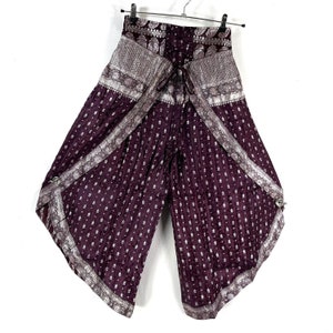 May include: Plum-colored palazzo pants with a silver paisley and floral pattern. The wide-leg pants have a drawstring waist and decorative silver trim along the edges. The fabric has a subtle sheen, and the pants are hanging on a black hanger.