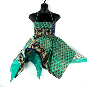 Puede incluir: Un vestido halter estampado en verde, azul y marrón con un corpiño fruncido y una falda fluida. El vestido está hecho de una tela ligera y tiene un corte holgado.