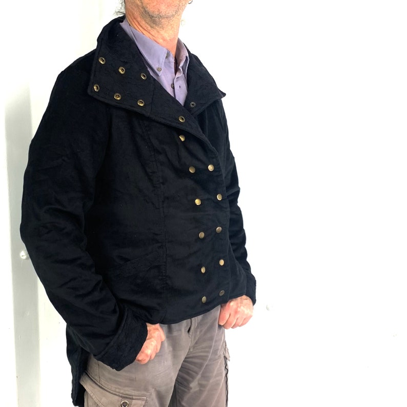 May include: A black jacket with a high collar and gold button accents. The jacket has a double-breasted closure and a long, flowing style.