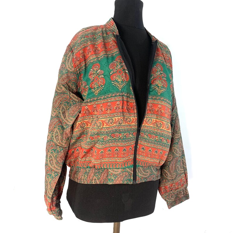 May include: A red, green, and gold patterned bomber jacket with a zipper closure.