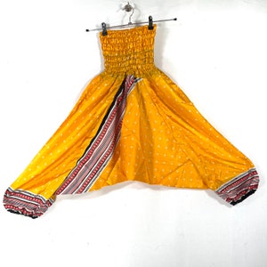 May include: Yellow harem pants with a white polka dot pattern and a black, red, and white striped trim. The pants have an elastic waistband and a loose, flowing fit.