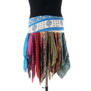 May include: A colorful, patchwork skirt with a wide elastic waistband. The skirt features panels of various colors and patterns, including blue, pink, red, and green. The skirt is displayed on a mannequin and has a unique, asymmetrical hemline.