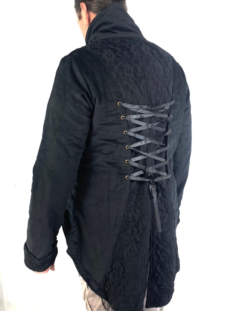 May include: Black long-sleeved jacket with a lace back panel and a corset-style lacing detail. The jacket has a high collar and a long, pointed tail.