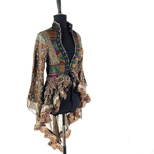 May include: A patterned brown, green, and purple jacket with a high collar and flared sleeves. The jacket features a lace-up front and ruffled detailing along the waist and hem. The jacket is displayed on a black mannequin.