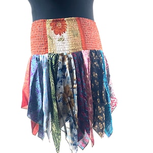 May include: A patchwork skirt with a vibrant mix of colors and patterns. The waistband is orange and gold, with a floral design. The skirt's lower portion features various fabrics in shades of blue, purple, green, and red, creating a bohemian style.