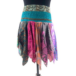 May include: A colorful, bohemian-style skirt with a tiered design. The skirt features a patterned, patchwork design in shades of teal, pink, orange, purple, and green. The skirt has an elastic waistband and a flowing, asymmetrical hemline.