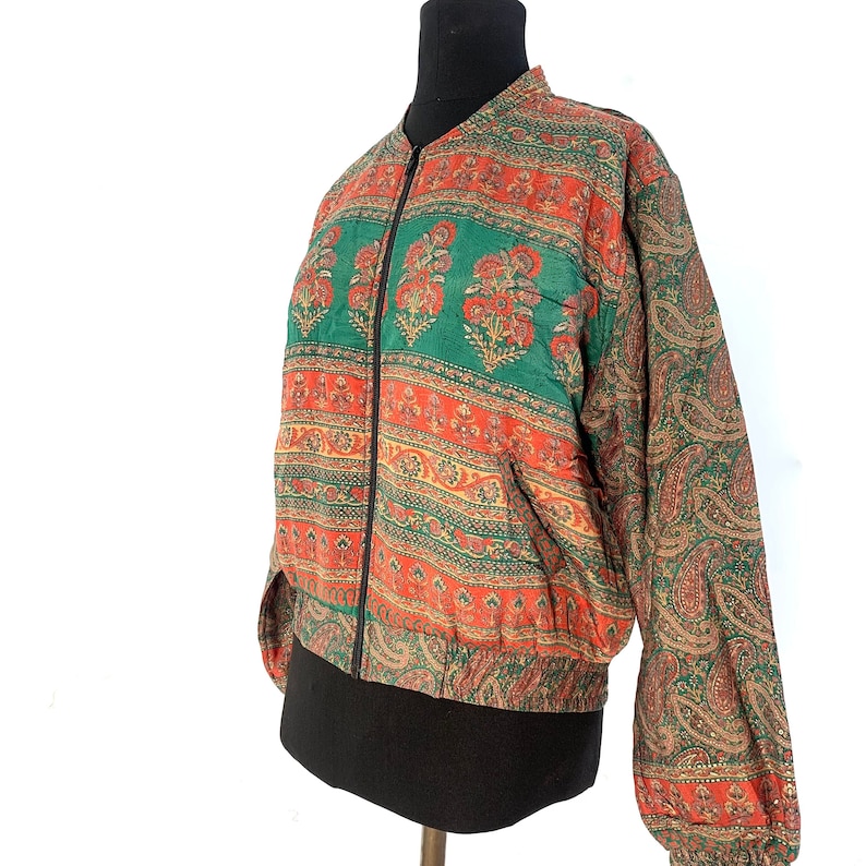 May include: A green and orange patterned bomber jacket with a zipper closure. The jacket has a paisley pattern on the sleeves.