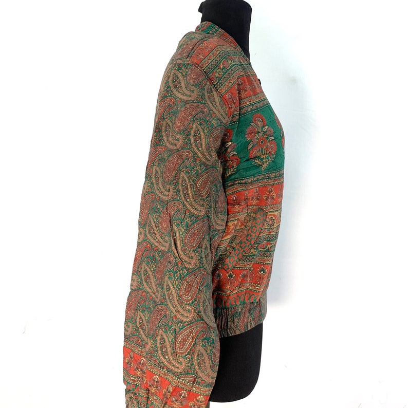 May include: A green, orange, and brown paisley patterned bomber jacket with a zipper closure.
