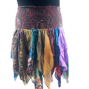 May include: A colorful, patchwork skirt with a smocked waistband. The skirt features a variety of patterned fabrics in shades of blue, purple, gold, and brown. The skirt has a flowing, asymmetrical hemline.