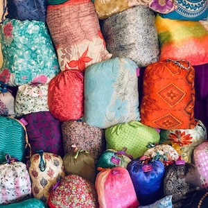 May include: A collection of colorful fabric pouches with various patterns and designs. The pouches are made of different materials, including cotton, silk, and velvet. They are arranged in a pile, with some overlapping. The pouches are a variety of sizes and shapes, and they are all closed.