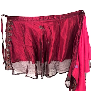 Könnte beinhalten: Ein Wickelrock in Burgunderrot und Fuchsia. Der Rock hat eine transparente, dunkelburgunderfarbene Unterschicht und bestickte Details. Er hat einen Bindverschluss. Der Rock ist zum Wickeln um die Taille gedacht.