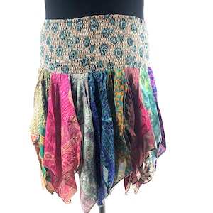 May include: A colorful, bohemian-style skirt with a patterned elastic waistband. The skirt features panels of vibrant fabric in shades of pink, blue, green, and orange, creating a layered, flowing effect. The skirt is designed to be worn at the waist.