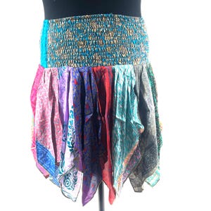 May include: A colorful patchwork skirt with a turquoise and gold elastic waistband. The skirt features a variety of patterned fabrics in shades of pink, purple, red, and teal. The skirt has a unique, flowing design.
