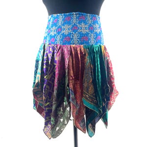 May include: A colorful, patchwork skirt with a blue, patterned elastic waistband. The skirt features panels of various colors and patterns, including purple, pink, green, and red. The skirt is designed to be worn at the waist.