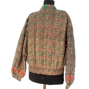 May include: A green and brown paisley patterned bomber jacket with a ribbed waistband and cuffs.