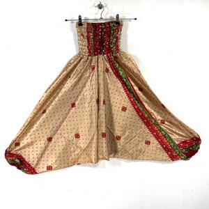 May include: Beige, red, and green patterned pants with an elastic waistband. The pants have a wide leg and a loose fit.