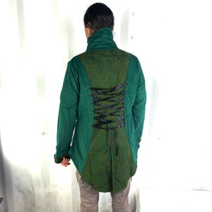 May include: A green jacket with a black lace-up back detail. The jacket has a high collar and long sleeves.