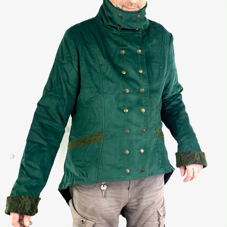 May include: A dark green velvet jacket with a high collar and gold buttons. The jacket has a long tail and decorative trim on the sleeves and hem.