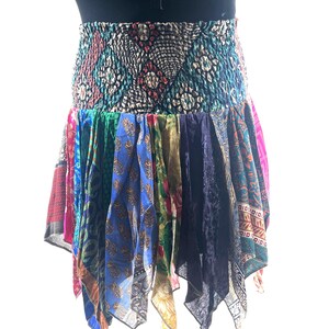 May include: A colorful, patchwork skirt with a patterned elastic waistband. The skirt features a variety of fabrics in shades of blue, pink, green, and gold. The skirt's length is approximately 18 inches.