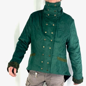 May include: A dark green jacket with a high collar and gold buttons. The jacket has a fitted silhouette and a slightly longer back.