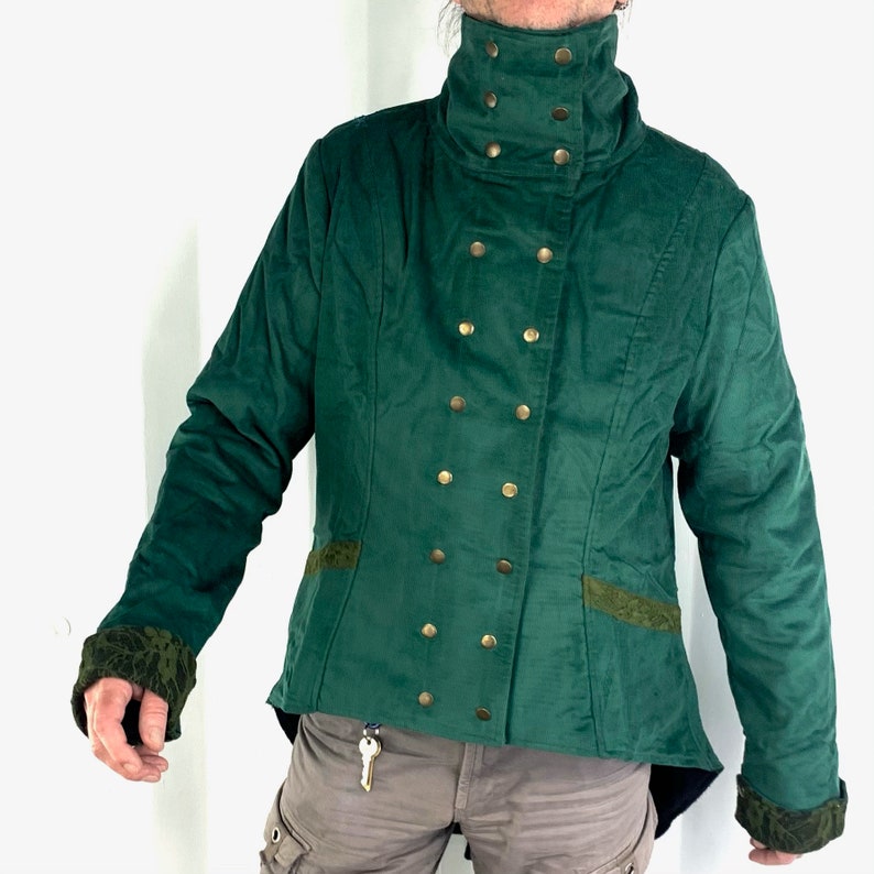 May include: A dark green jacket with a high collar and gold buttons. The jacket has a fitted silhouette and a slightly longer back.