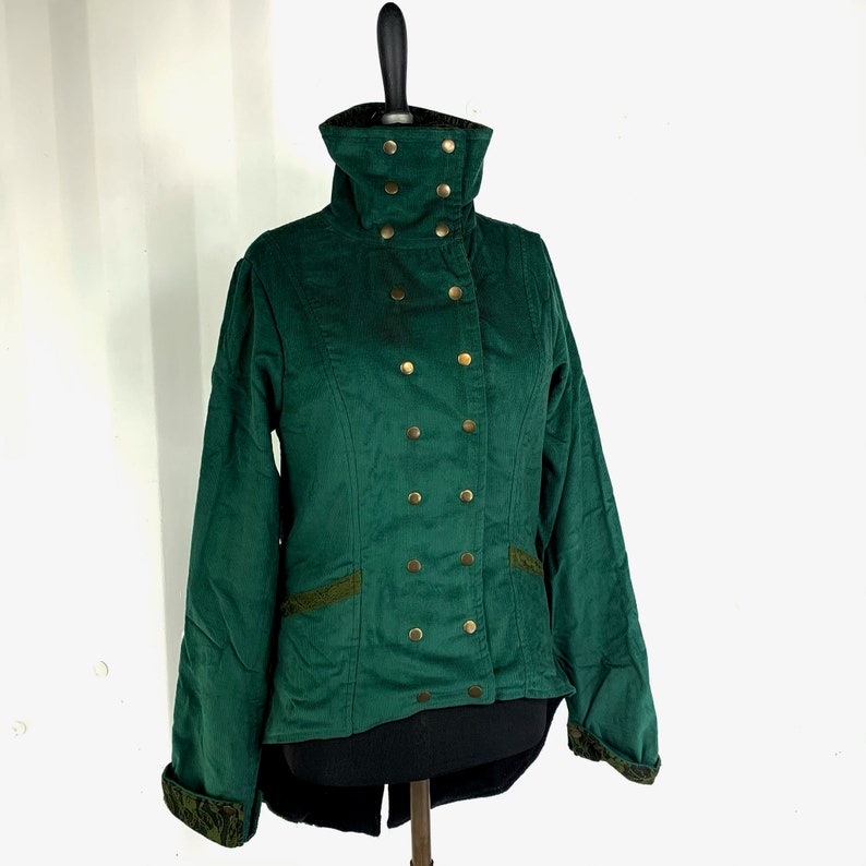 May include: A dark green jacket with a high collar and gold buttons. The jacket has a long back and a fitted waist.